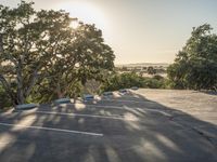 a empty parking lot with two cars in the background and trees on both sides of the parking lot