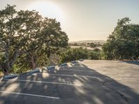 a empty parking lot with two cars in the background and trees on both sides of the parking lot