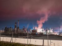 an empty parking lot with some power plants behind it on a stormy day at night