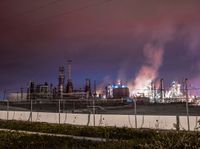 an empty parking lot with some power plants behind it on a stormy day at night