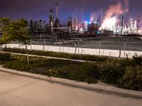 an empty parking lot with some power plants behind it on a stormy day at night