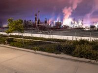 an empty parking lot with some power plants behind it on a stormy day at night