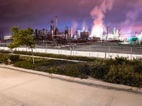 an empty parking lot with some power plants behind it on a stormy day at night