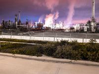 an empty parking lot with some power plants behind it on a stormy day at night