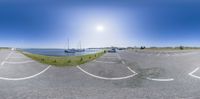 a fisheye photo shows an empty parking lot and boats on a calm lake shore