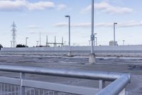 an empty parking lot with white fence and street lights in the background on the road