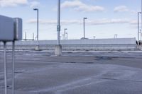 an empty parking lot with white fence and street lights in the background on the road