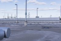 an empty parking lot with white fence and street lights in the background on the road