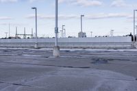 an empty parking lot with white fence and street lights in the background on the road