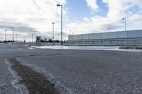 an empty parking lot with snow, ice and electric poles in the background of a wall