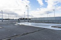 an empty parking lot with snow, ice and electric poles in the background of a wall