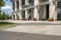 an empty parking lot with a canopy over the street, surrounded by many different planters and flowers