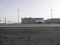 cars parked in an empty lot with an outside billboard on a building in the back ground