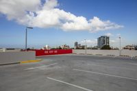 a empty parking lot with a red sign in it and high rise buildings in the background