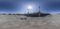 a fish - eye lens photo of a empty parking lot, the sun is shining down on it