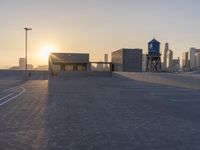 an empty parking lot with a view of the city at sunset behind it during the day