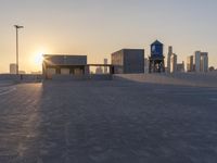 an empty parking lot with a view of the city at sunset behind it during the day