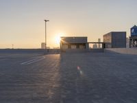 an empty parking lot with a view of the city at sunset behind it during the day