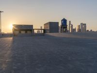 an empty parking lot with a view of the city at sunset behind it during the day