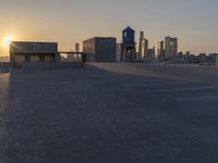 an empty parking lot with a view of the city at sunset behind it during the day