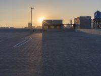 an empty parking lot with a view of the city at sunset behind it during the day