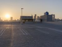 an empty parking lot with a view of the city at sunset behind it during the day