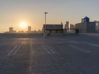 an empty parking lot with a view of the city at sunset behind it during the day