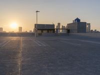 an empty parking lot with a view of the city at sunset behind it during the day