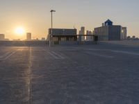 an empty parking lot with a view of the city at sunset behind it during the day