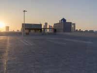 an empty parking lot with a view of the city at sunset behind it during the day