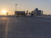 an empty parking lot with a view of the city at sunset behind it during the day