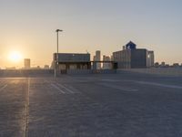 an empty parking lot with a view of the city at sunset behind it during the day