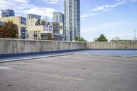 empty parking lot next to tall buildings with blue sky and clouds in the background in a city