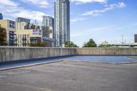 empty parking lot next to tall buildings with blue sky and clouds in the background in a city