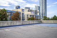 empty parking lot next to tall buildings with blue sky and clouds in the background in a city