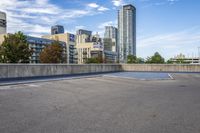 empty parking lot next to tall buildings with blue sky and clouds in the background in a city