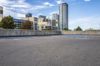 empty parking lot next to tall buildings with blue sky and clouds in the background in a city