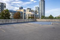 empty parking lot next to tall buildings with blue sky and clouds in the background in a city