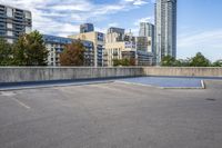 empty parking lot next to tall buildings with blue sky and clouds in the background in a city