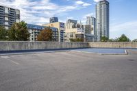 empty parking lot next to tall buildings with blue sky and clouds in the background in a city