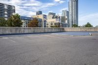 empty parking lot next to tall buildings with blue sky and clouds in the background in a city