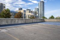 empty parking lot next to tall buildings with blue sky and clouds in the background in a city