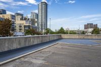 empty parking lot next to tall buildings with blue sky and clouds in the background in a city