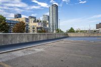 empty parking lot next to tall buildings with blue sky and clouds in the background in a city