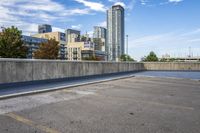 empty parking lot next to tall buildings with blue sky and clouds in the background in a city