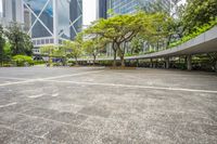 an empty parking lot filled with plants and trees in a city setting in front of a tall glass building