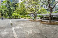 an empty parking lot filled with plants and trees in a city setting in front of a tall glass building