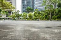 an empty parking lot filled with plants and trees in a city setting in front of a tall glass building