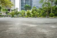 an empty parking lot filled with plants and trees in a city setting in front of a tall glass building