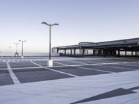 a empty parking lot with a very tall building in the background and streetlights on each side